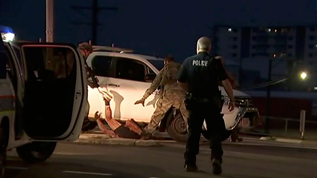 In this image made from video, police proceed to apprehend a suspect on the ground next to a white truck, Tuesday, June 4, 2019, in Darwin Australia. 