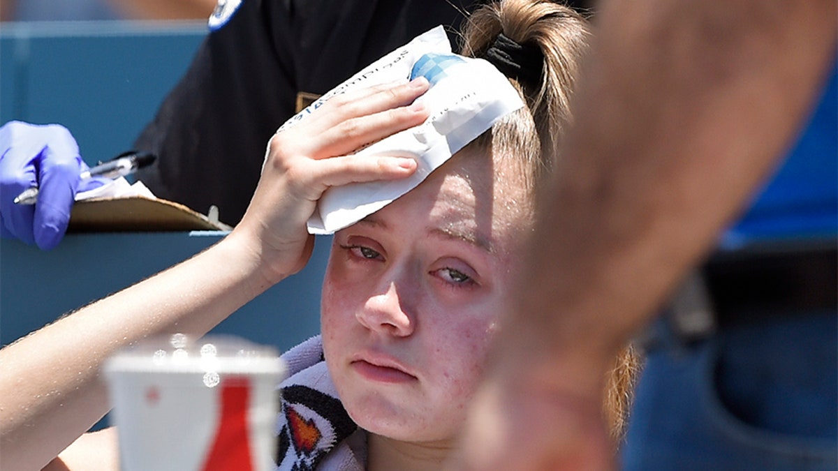 A young fan holds ice to her head after being hit with a foul ball hit by Los Angeles Dodgers' Cody Bellinger during the first inning of a baseball game against the Colorado Rockies on Sunday.
