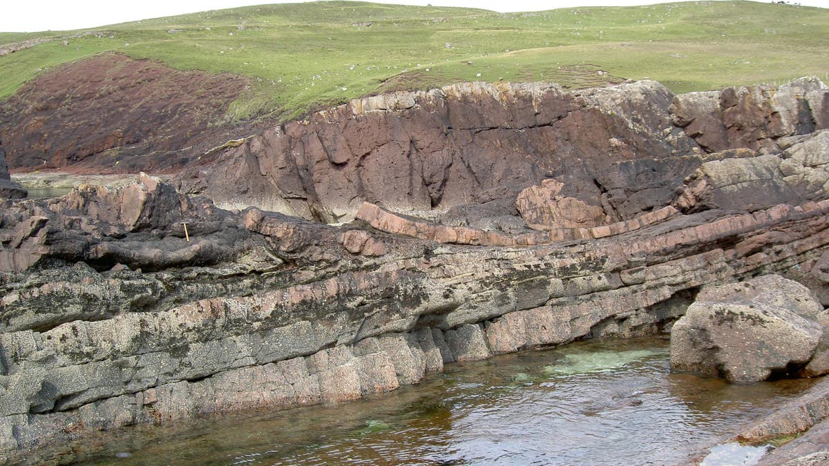 A field photo taken at Stoer showing the laminar beds of sandstone, in the middle of which is the impact deposit left by the asteroid. (Handout/PR)
