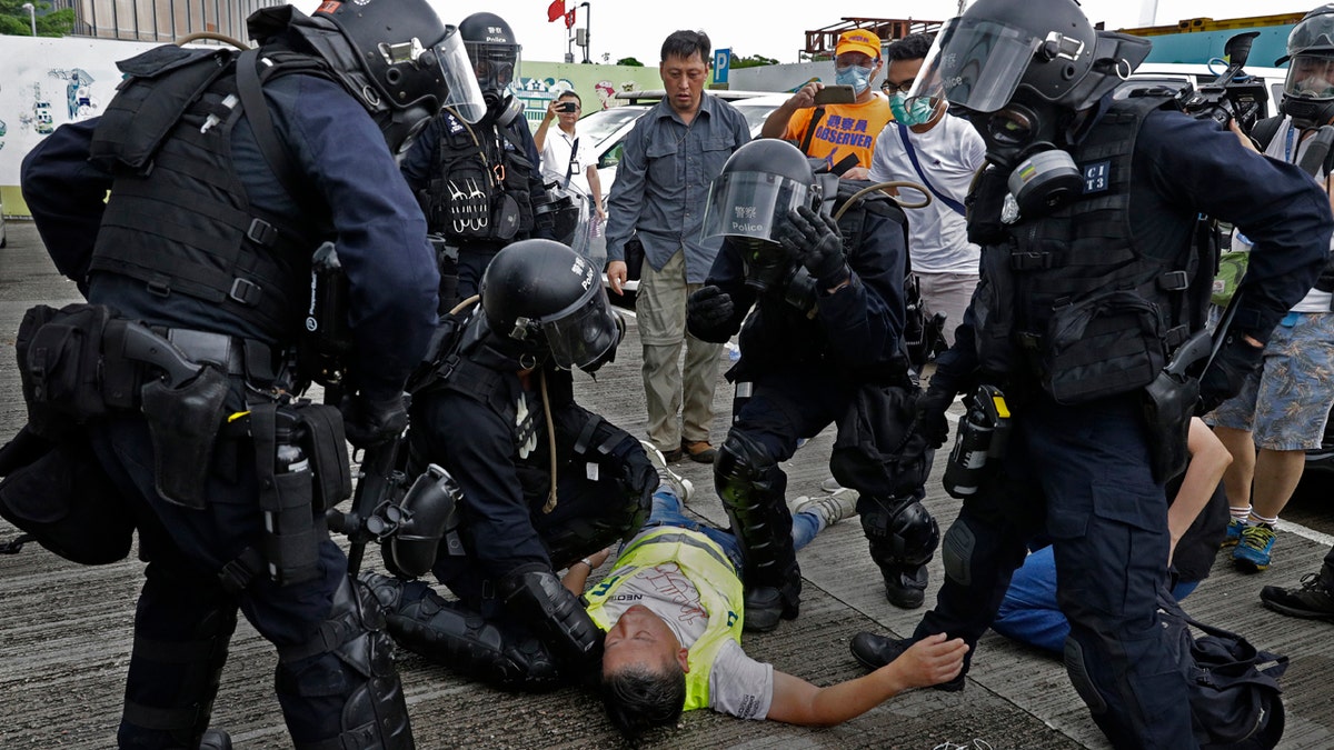 In this file photo taken Wednesday, June 12, 2019, a cameraman lies injured after riot police fire tear gas on protesters outside the Legislative Council in Hong Kong.