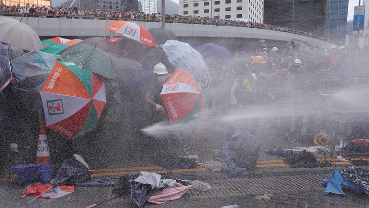 Protesters are hit by police water cannon during a demonstration against a proposed extradition bill in Hong Kong, China, using only their umbrellas as protection