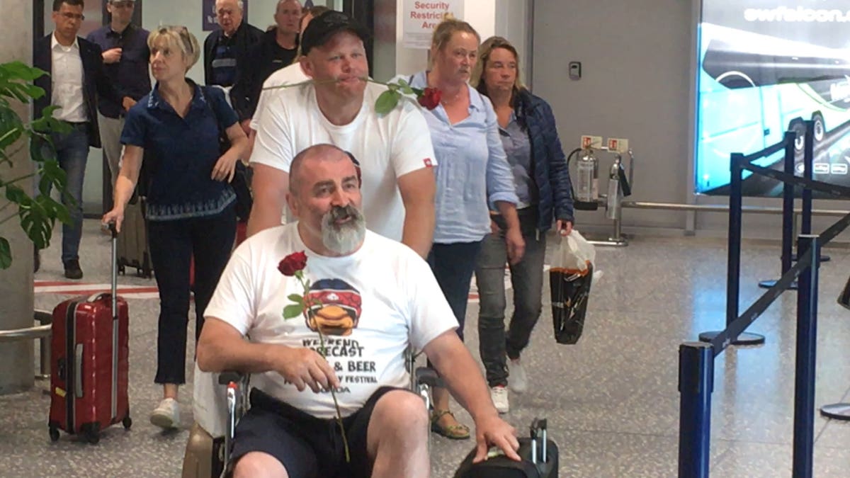 As Mark’s friends exited the aircraft, each one approached the waiting Julie and handed her a single rose.