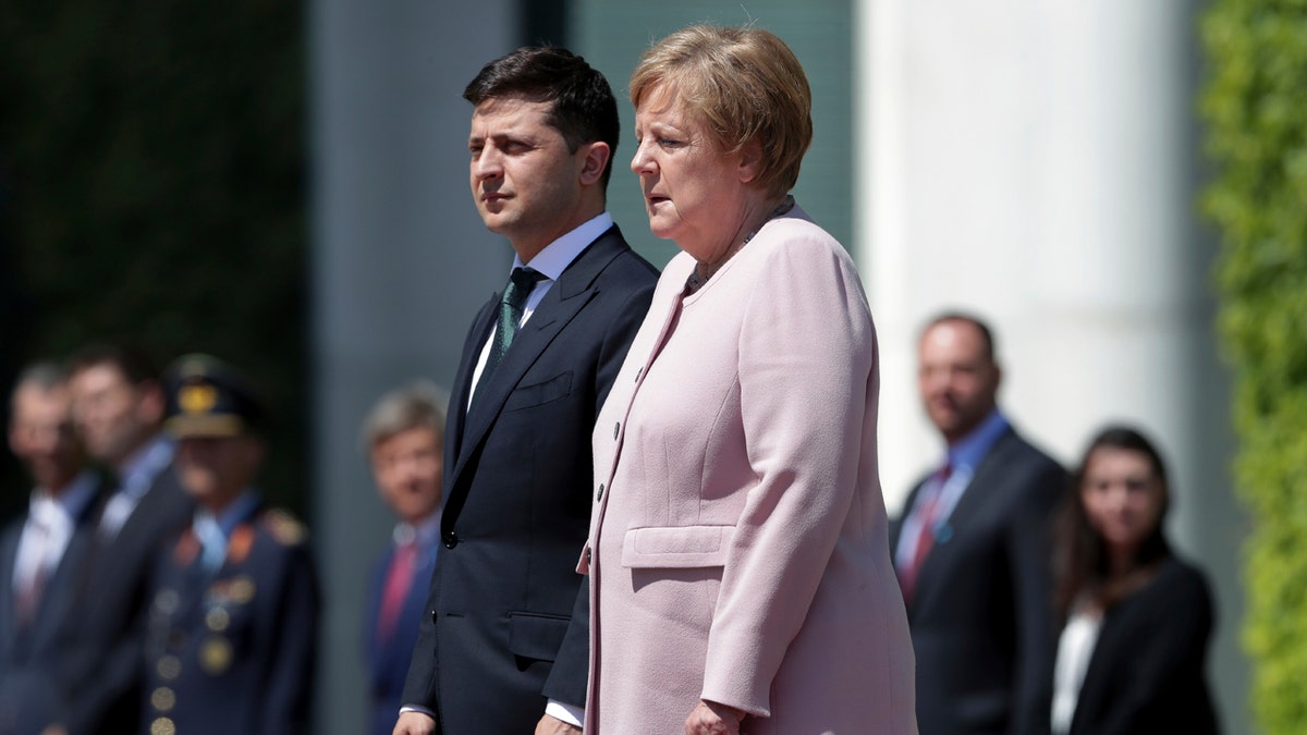 German Chancellor Angela Merkel, right, trembles strong as she and Ukraine's President Volodymyr Zelenskiy, left, attend the national anthems as part of a military welcome ceremony in Berlin, Germany. AP Photo/Michael Sohn
