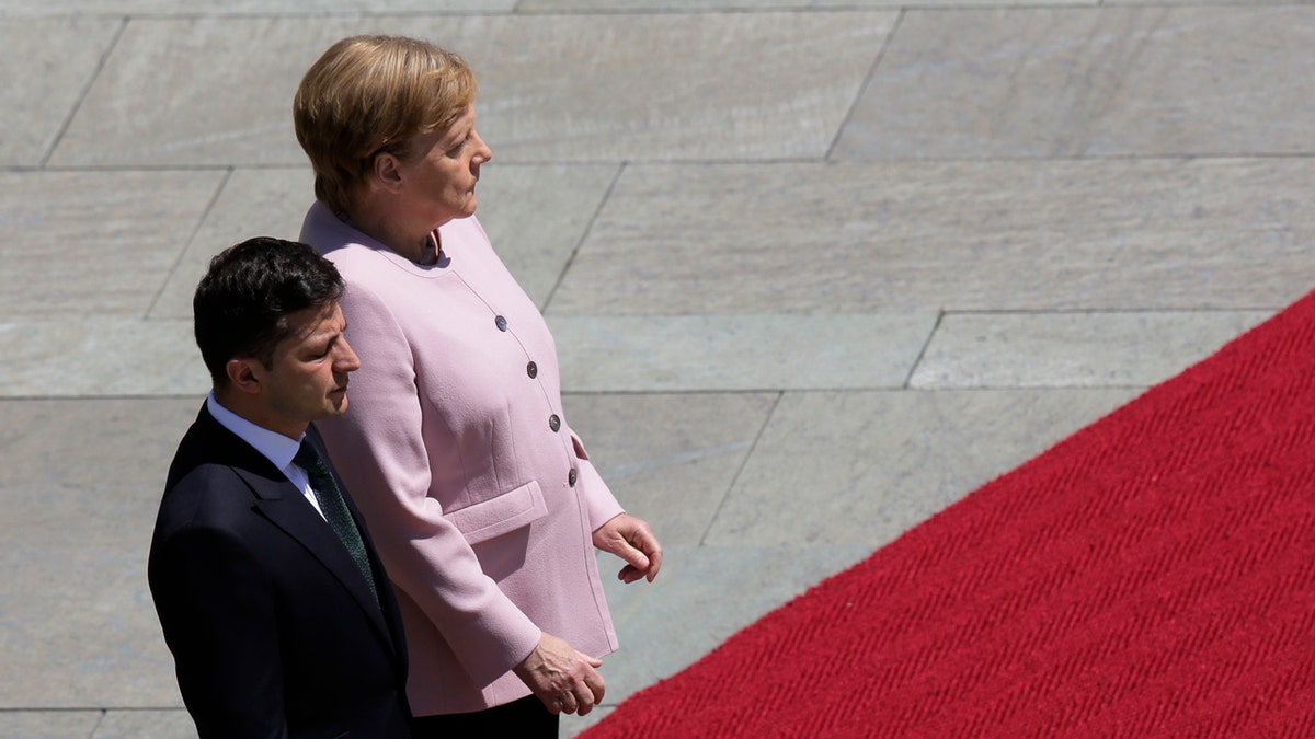 German Chancellor Angela Merkel, right, and Ukrainian President Volodymyr Zelenskiy, left, listen to the national anthems during the welcoming ceremony, prior to a meeting at the chancellery in Berlin, Germany, Tuesday, June 18, 2019.