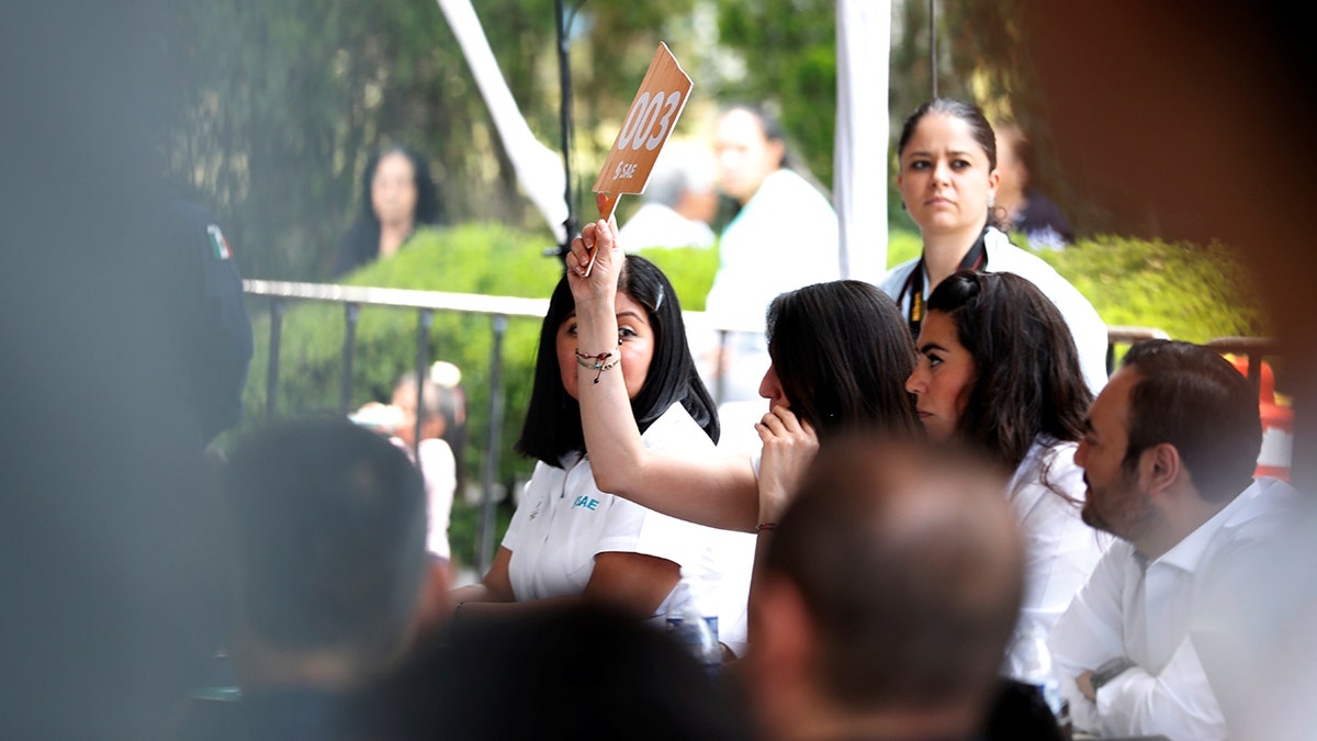 A woman bids during an auction of seized properties from drug traffickers and others, in Mexico City, Mexico June 23, 2019.