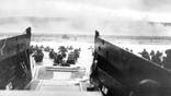 FILE - In this June 8, 1944, file photo, under heavy German machine gun fire, American infantrymen wade ashore off the ramp of a Coast Guard landing craft during the invasion of the French coast of Normandy in World War II. June 6, 2019, marks the 75th anniversary of D-Day, the assault that began the liberation of France and Europe from German occupation, leading to the end World War II.