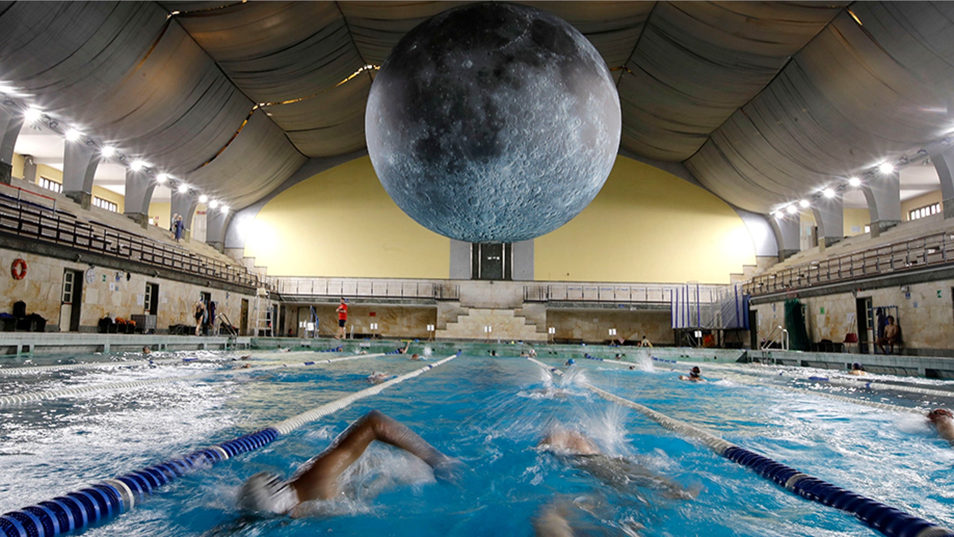 Swimmers practice as the installation 'Museum of the Moon', a seven meters diameter reproduction of the moon by British artist Luke Jerramche, is suspended above the Cozzi swimming pool in Milan, Italy, June 15, 2019. 