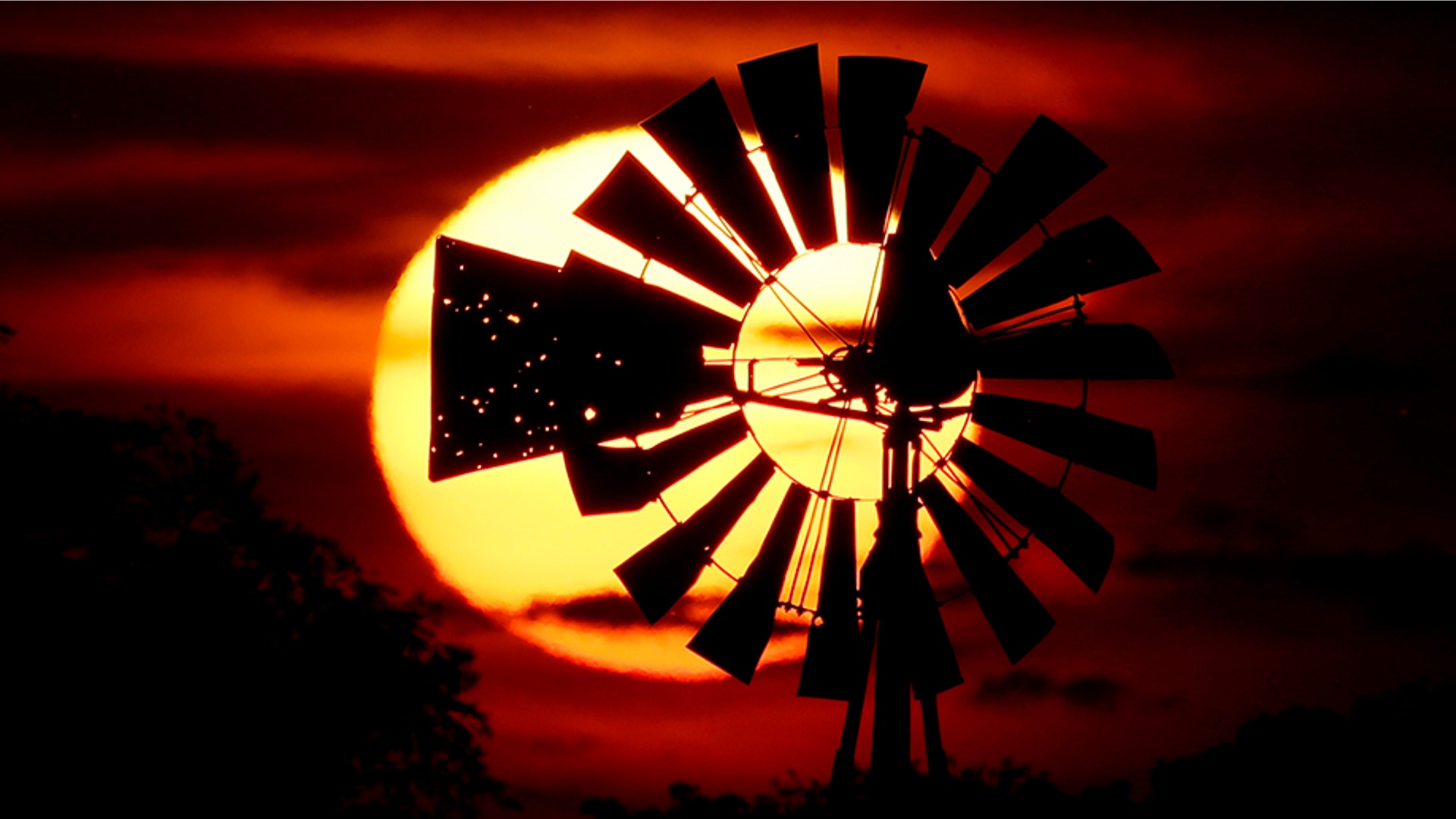 The sun sets behind a tattered windmill near Tappen, North Dakota, June 18, 2019. 