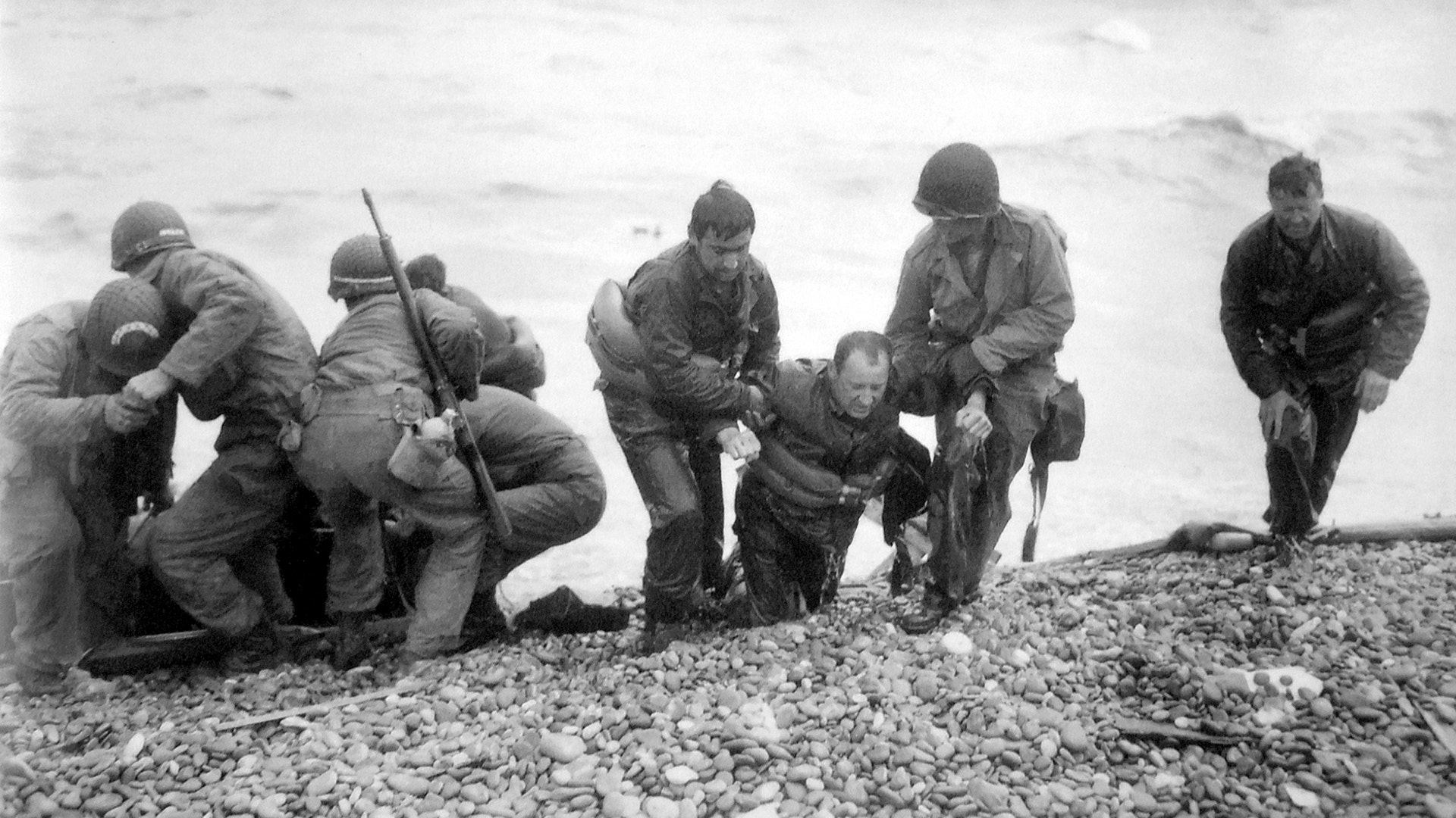 Soldiers carry troop onto beach during D-Day