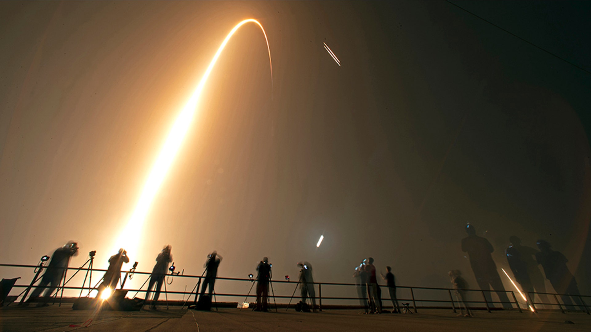 Photographers capture the launch and rocket boosters landing of a SpaceX Falcon heavy rocket at the Kennedy Space Center in Cape Canaveral, Florida, June 25, 2019. 