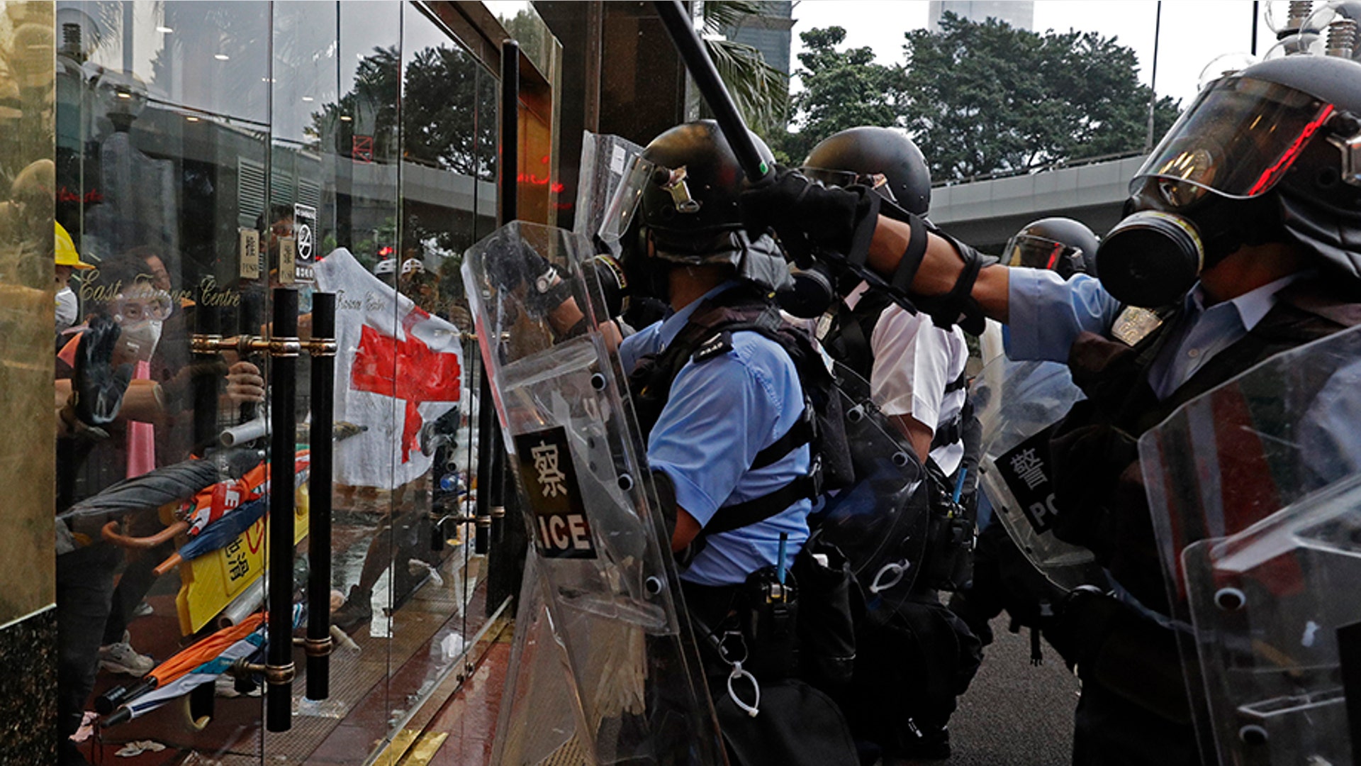 Riot police run toward protesters inside the front entrance of a building outside the Legislative Council in Hong Kong, June 12, 2019. 
