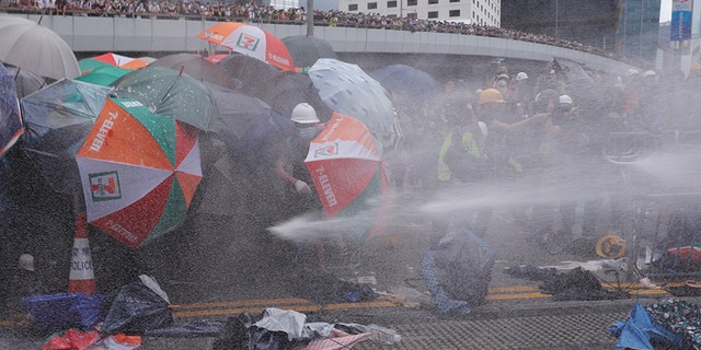 Protesters are hit by police water cannon during a demonstration against a proposed extradition bill in Hong Kong, China June 12, 2019. REUTERS/Tyrone Siu - RC12C6522E40