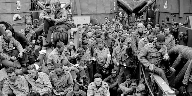 U.S. servicemen attend a service aboard a landing craft before the D-Day invasion on the coast of France.​​​​​​​