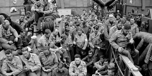 American servicemen huddle on D-Day war ship.