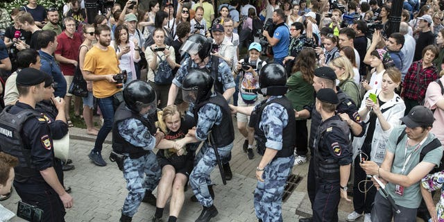 Police officers detain a protester during a march in Moscow, Russia, Wednesday, June 12, 2019. Police and hundreds of demonstrators are facing off in central Moscow at an unauthorized march against police abuse in the wake of the high-profile detention of a Russian journalist.
