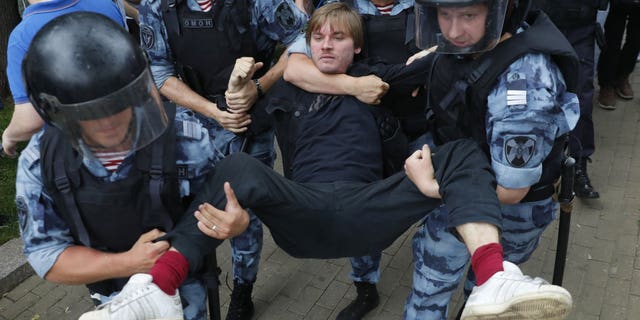 Police officers detain a protester during a march in Moscow, Russia, Wednesday, June 12, 2019. Police and hundreds of demonstrators are facing off in central Moscow at an unauthorized march against police abuse in the wake of the high-profile detention of a Russian journalist. More than 20 demonstrators have been detained, according to monitoring group.