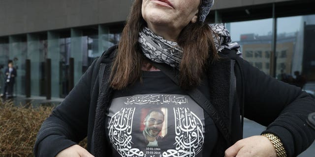 Janna Ezat, mother of Al Noor mosque shooting victim, Hussein Al-Umari shows a shirt bearing his photo outside the Christchurch District Court in Christchurch, New Zealand, Friday, June 14, 2019. Brenton Tarrant, the man accused of killing 51 people at two Christchurch mosques on March 15, 2019, pleaded not guilty to all the charges filed against him Friday June 14.