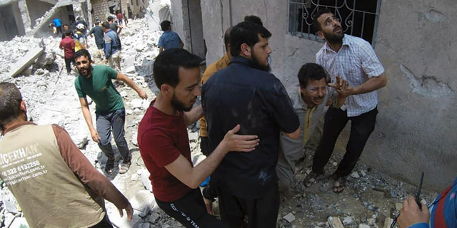 This photo posted and provided by the Syrian Civil Defense White Helmets, which has been authenticated based on its contents and other AP reporting, shows Syrians gathering at the scene where an airstrike by Syrian government forces hit the town of Jabal al-Zawiya in Idlib province, Syria, Saturday, June 15, 2019. Syrian opposition activists say government airstrikes on rebel-held areas in northwestern Syrian and intense fighting claimed the lives dozens of people. (Syrian Civil Defense White Helmets via AP)