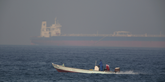 A fishing boat speeds past an oil tanker in the distance in Fujairah, United Arab Emirates, Saturday, June 15, 2019. The Kokuka Courageous, one of two oil tankers targeted in an apparent attack in the Gulf of Oman, was brought to the United Arab Emirates' eastern coast Saturday. (AP Photo/Jon Gambrell)