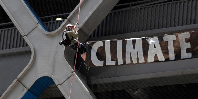 A man rappels down the side of the Port Authority Building with a sign during a climate change rally outside of the New York Times building, Saturday, June 22, 2019, in New York. Activists blocked traffic along 8th Avenue during a sit-in to demand coverage of climate change by the newspaper. (AP Photo/Julio Cortez)