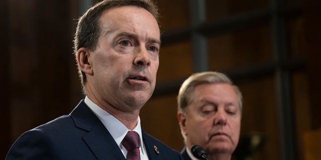 FILE - In this May 15, 2019, file photo, acting U.S. Customs and Border Protection Commissioner John Sanders, left, joins Senate Judiciary Committee Chairman Lindsey Graham, R-S.C., right, on Capitol Hill in Washington. Sanders says he's stepping down amid outrage over his agency's treatment of detained migrant children and said in a message to CBP employees Tuesday that he would resign on July 5. (AP Photo/J. Scott Applewhite)