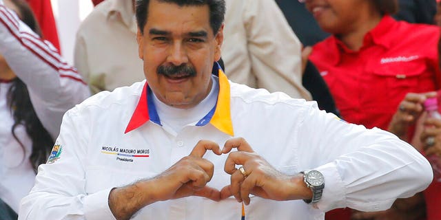 In this photo from May 20, Venezuela's President Nicolas Maduro shows a symbol of the hand and heart to followers in front of the Miraflores Presidential Palace in Caracas. (AP Photo / Ariana Cubillos)