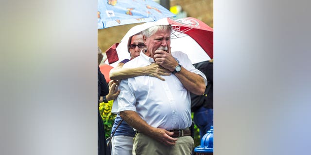 Frank Janes is comforted by his wife, Cathie Janes, during the prayer vigil at Strawbridge Marketplace in response to a shooting at a municipal building in Virginia Beach, Va., Saturday, June 1, 2019. A longtime city employee opened fire at the building Friday before police shot and killed him, authorities said. (Daniel Sangjib Min/Richmond Times-Dispatch via AP)