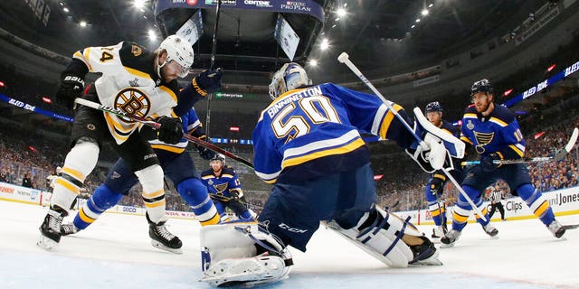 St. Louis Blues goaltender Jordan Binnington (50) catches the puck as Boston Bruins left wing Jake DeBrusk (74) watches for the rebound.
