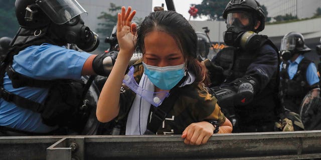 A protester reacts as she tackled by riot police during a massive demonstration outside the Legislative Council in Hong Kong, Wednesday, June 12, 2019. Hong Kong police have used tear gas and high-pressure hoses against thousands of protesters opposing a highly controversial extradition bill outside government headquarters.