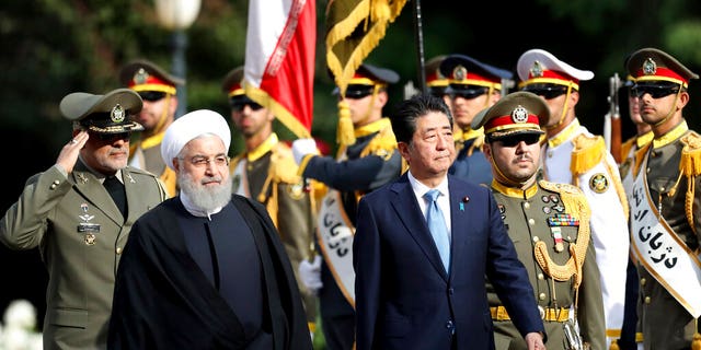 Japanese Prime Minister Shinzo Abe, center, reviews an honor guard as he is welcomed by Iranian President Hassan Rouhani, left, in an official arrival ceremony at the Saadabad Palace in Tehran.
