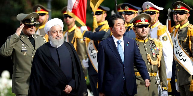 Japanese Prime Minister Shinzo Abe, center, reviews an honor guard as he is welcomed by Iranian President Hassan Rouhani, left, in an official arrival ceremony at the Saadabad Palace in Tehran.