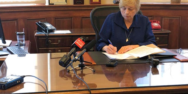 Maine Gov. Janet Mills signs a bill Wednesday that makes hers the eighth state to allow terminally ill people to end their lives with prescribed medication. (AP Photo/Marina Villeneuve)