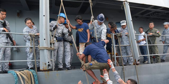 Rescued Filipino fishermen transfer to another ship as they head back to shore in Occidental Mindoro province, Philippines on Friday June 14, 2019.