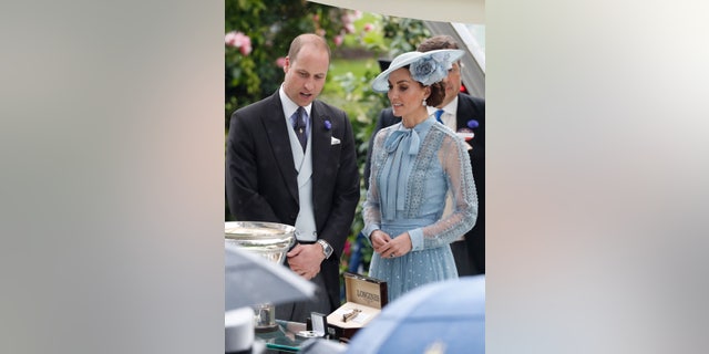 British Prince William and the Duchess of Cambridge, Kate, stand beside the trophies on the first day of the annual Royal Ascot horse race in Ascot, England on June 18, 2019. (AP Photo / Alastair Grant)