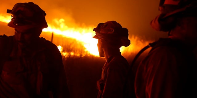 In this Sept. 12, 2015 file photo, California Department of Corrections and Rehabilitation inmates stand guard as flames from the Butte Fire approach a containment line near San Andreas, Calif. Attorneys representing 14 local governments said Tuesday, June 18, 2019 that they had reached a $1 billion settlement with California utility Pacific Gas & Electric for a series of fires dating to 2015. (AP Photo/Rich Pedroncelli, File)