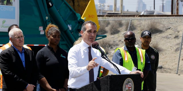 Los Angeles Mayor Eric Garcetti, at podium, surrounded by city sanitation workers, speaks about the city's homelessness problem at a news conference in Los Angeles on June 19, 2019. Far left, is city councilman, Mike Bonin. (AP Photo/Damian Dovarganes)