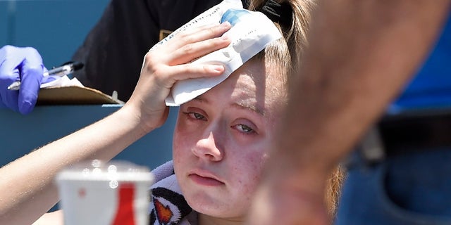 A young fan holds ice to her head after being hit with a foul ball hit by Los Angeles Dodgers' Cody Bellinger during the first inning of a baseball game against the Colorado Rockies, Sunday, June 23, 2019, in Los Angeles. (AP Photo/Mark J. Terrill)