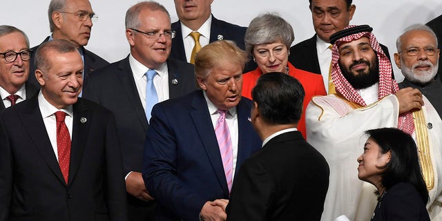 President Donald Trump, center, shakes hands with Chinese President Xi Jinping, as they gather for a group photo at the G-20 summit in Osaka, Japan, on Friday. (Associated Press)