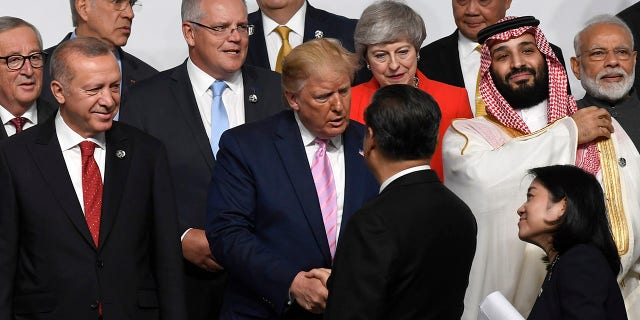 President Donald Trump, center, shakes hands with Chinese President Xi Jinping, as they gather for a group photo at the G-20 summit in Osaka, Japan, on Friday. (Associated Press)