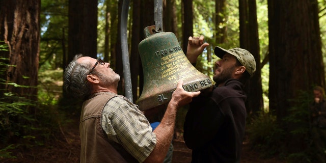 David Jessen, left, and Mitch Smith, both UC Santa Cruz employees, officially remove an El Camino Real bell marker from campus during a ceremony on Friday, June 21, 2019, in Santa Cruz, Calif. (AP Photo/Cody Glenn)