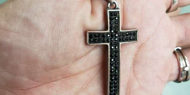 Maria Branon holds her son's cross on his necklace. They both wear them all the time and credit God for saving him Sunday after falling 50 feet from a bluff.