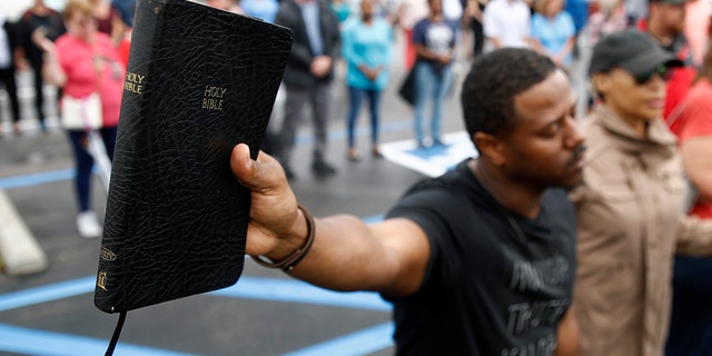 Mike Harris, of Virginia Beach, Va., holds a Bible as he prays during a vigil in response to a shooting at a municipal building. A longtime city employee opened fire at the building Friday before police shot and killed him, authorities said. (AP Photo/Patrick Semansky)