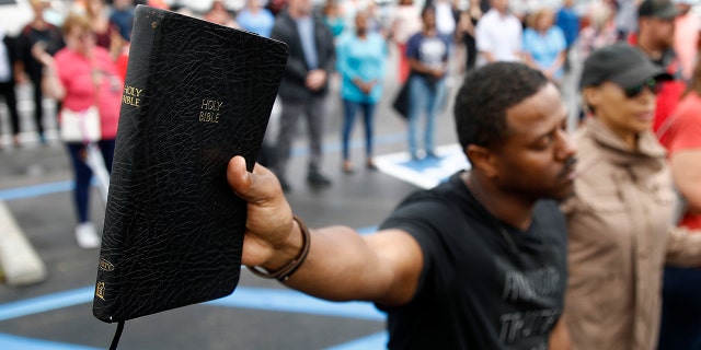 Mike Harris, of Virginia Beach, Va., holds a Bible as he prays during a vigil in response to a shooting at a municipal building. A longtime city employee opened fire at the building Friday before police shot and killed him, authorities said. (AP Photo/Patrick Semansky)