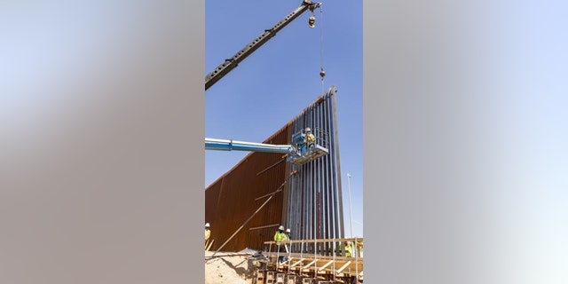 Workers install the first panels of the Calexico border wall project