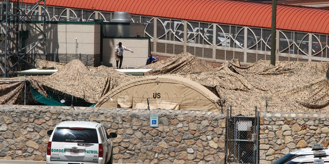 In this June 7, 2019, photo, migrants adjust a shade canopy over an outdoor encampment where they're waiting to be processed by immigration in El Paso, Texas. The Trump administration is facing growing complaints from migrants about severe overcrowding, meager food and other hardships at border holding centers like this one. (AP Photo/Cedar Attanasio)