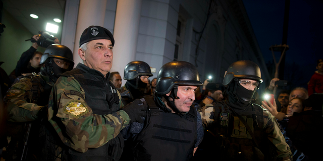 FILE - In this June 14, 2016 file photo, former Public Works Secretary Jose Lopez, center, is escort by police outside the a police station in the outskirts of Buenos Aires, Argentina. A court in Argentina sentenced Lopez on Wednesday, June 12, 2019, to 6 years in prison for illicit enrichment after he tried to hide millions of dollars in cash at a convent. (AP Photo/Natacha Pisarenko, File)