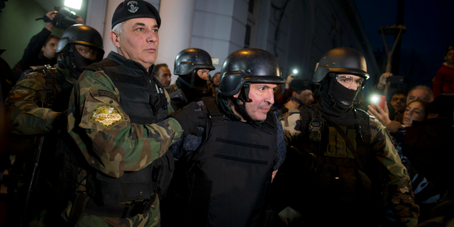 FILE - In this June 14, 2016 file photo, former Public Works Secretary Jose Lopez, center, is escort by police outside the a police station in the outskirts of Buenos Aires, Argentina. A court in Argentina sentenced Lopez on Wednesday, June 12, 2019, to 6 years in prison for illicit enrichment after he tried to hide millions of dollars in cash at a convent. (AP Photo/Natacha Pisarenko, File)
