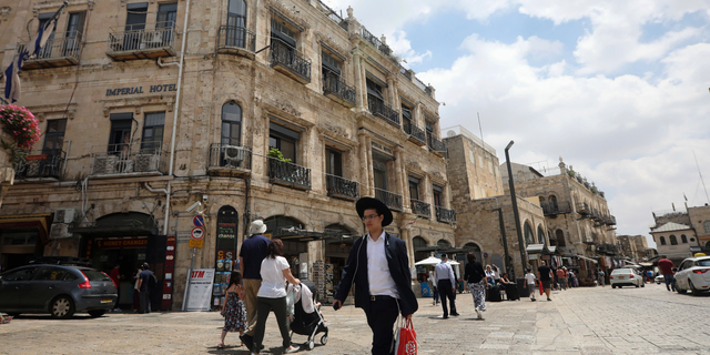 People walk past the Palestinian-run Imperial Hotel, that was part of a legal battle, in Jerusalem's Old City, Thursday, June 13, 2019. Israel's Supreme Court has ruled against the Greek Orthodox Church in a long-running legal battle over the sale of three properties in predominantly Palestinian parts of Jerusalem's Old City to a Jewish settler group. (AP Photo/Mahmoud Illean)