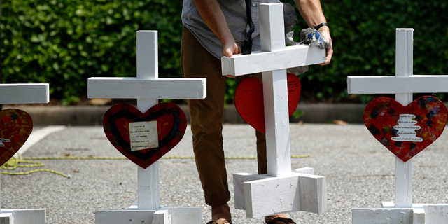 FILE - In this June 2, 2019, file photo, a volunteer prepares to place crosses for victims of a mass shooting at a municipal building in Virginia Beach, Va., at a nearby makeshift memorial. Police responding to the deadly mass shooting were unable to confront the gunman at one point because they didn’t have the key cards needed to open doors on the second floor. Whether the delay contributed to the death toll is unclear, but the episode illustrated how door-lock technology that is supposed to protect people can hamper police and rescue workers in an emergency. (AP Photo/Patrick Semansky, File)