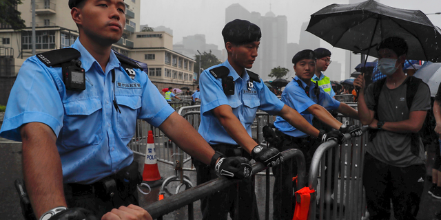 Policemen stand guard in the rain as protesters gather near the Legislative Council continuing protest against the unpopular extradition bill in Hong Kong, Monday, June 17, 2019. A member of Hong Kong's Executive Council says the city's leader plans to apologize again over her handling of a highly unpopular extradition bill. (AP Photo/Kin Cheung)
